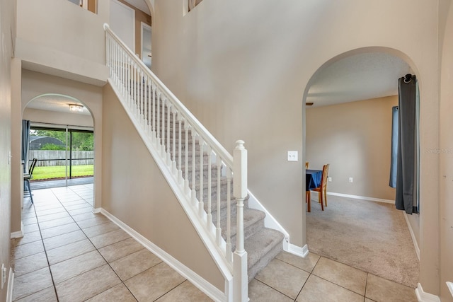 100 Monterey Oaks Dr, Sanford, FL 32771 - stairs featuring arched walkways, tile patterned floors, carpet floors, and a towering ceiling