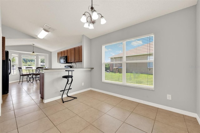 2713 Eagle Glen Cir, Kissimmee, FL 34746 - kitchen with lofted ceiling, a peninsula, pendant lighting, light tile patterned floors, and brown cabinetry