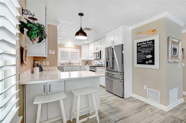 231 Ocean Blvd, Satellite Beach, FL 32937 - kitchen featuring stainless steel appliances, a peninsula, a textured ceiling, tasteful backsplash, and light countertops