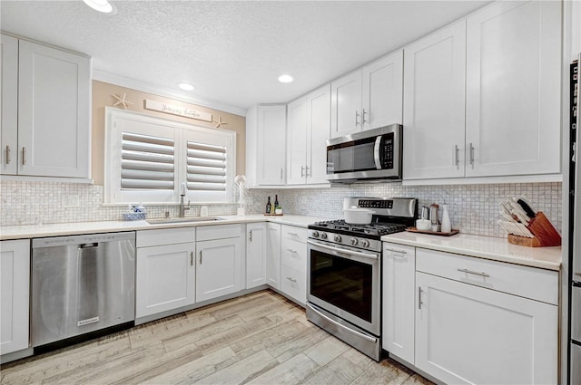 231 Ocean Blvd, Satellite Beach, FL 32937 - kitchen featuring stainless steel appliances, light countertops, white cabinetry, tasteful backsplash, and a textured ceiling