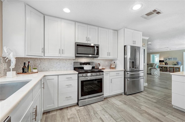 231 Ocean Blvd, Satellite Beach, FL 32937 - kitchen with appliances with stainless steel finishes, a textured ceiling, white cabinetry, light countertops, and tasteful backsplash