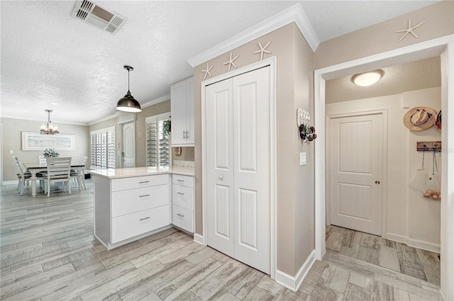 231 Ocean Blvd, Satellite Beach, FL 32937 - kitchen with a peninsula, a textured ceiling, white cabinets, light countertops, and a chandelier