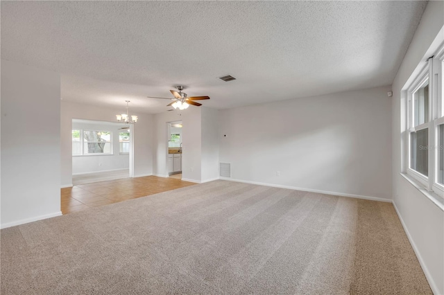 879 Tamerlane St, Deltona, FL 32725 - empty room featuring a chandelier, light carpet, a textured ceiling, ceiling fan, and light tile patterned floors