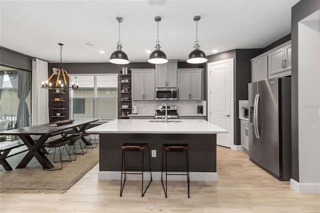 971 Braewood Dr, Clermont, FL 34715 - kitchen featuring stainless steel appliances, a chandelier, light countertops, light wood-type flooring, and a kitchen island with sink