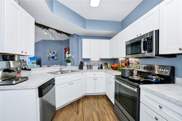 5566 Metrowest Blvd Unit 10, Orlando, FL 32811 - kitchen with stainless steel appliances, light countertops, light wood-style flooring, white cabinets, and track lighting