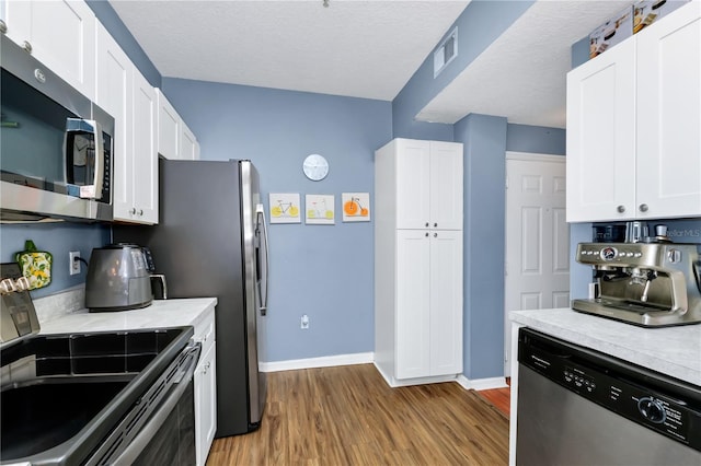 5566 Metrowest Blvd Unit 10, Orlando, FL 32811 - kitchen with appliances with stainless steel finishes, wood finished floors, light countertops, and white cabinetry