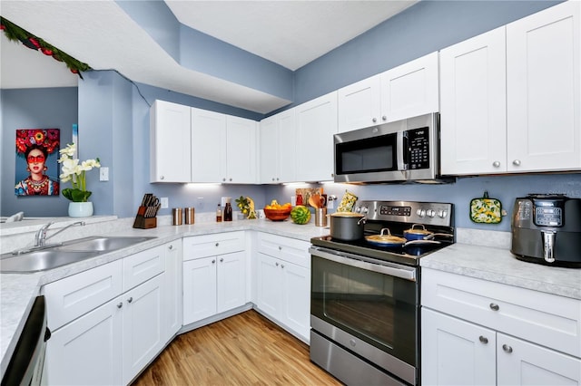 5566 Metrowest Blvd Unit 10, Orlando, FL 32811 - kitchen with appliances with stainless steel finishes, light countertops, light wood finished floors, and white cabinets