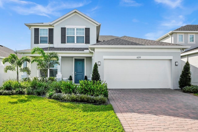 609 Big Pine Ave, Minneola, FL 34715 - view of front of property with stucco siding, decorative driveway, a front yard, an attached garage, and a shingled roof