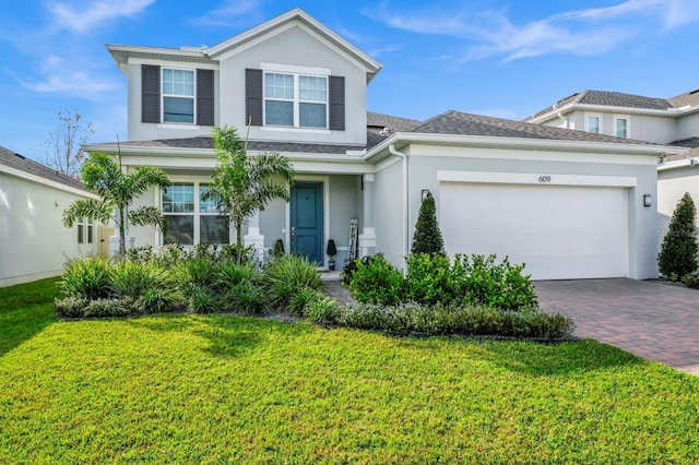 609 Big Pine Ave, Minneola, FL 34715 - traditional-style house with stucco siding, decorative driveway, a front lawn, and an attached garage