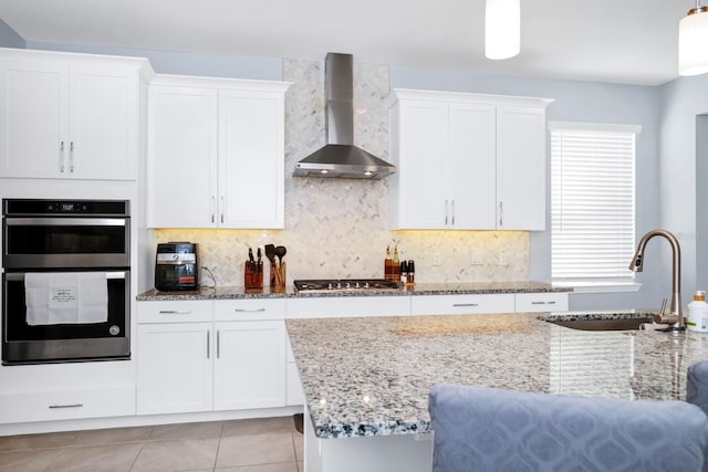609 Big Pine Ave, Minneola, FL 34715 - kitchen featuring wall chimney exhaust hood, multiple ovens, stainless steel gas cooktop, light stone counters, and white cabinetry
