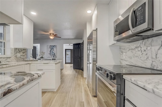 1921 Heathwood Dr, Winter Park, FL 32792 - kitchen with appliances with stainless steel finishes, white cabinetry, ceiling fan, decorative backsplash, and light wood finished floors