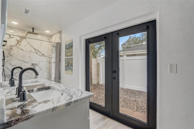 1921 Heathwood Dr, Winter Park, FL 32792 - full bathroom with french doors, double vanity, a marble finish shower, wood finished floors, and recessed lighting