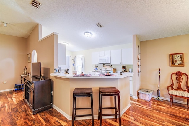 2031 Wekiva Reserve Blvd, Apopka, FL 32703 - kitchen with a breakfast bar, wood finished floors, white microwave, a peninsula, and a textured ceiling