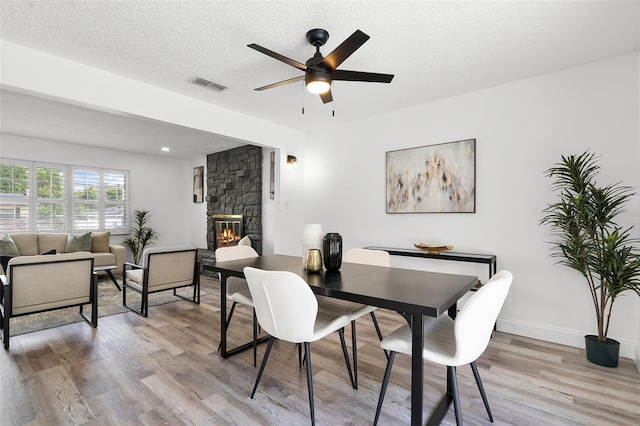 608 Pearl Rd, Winter Springs, FL 32708 - dining space featuring a fireplace, light wood-type flooring, ceiling fan, and a textured ceiling