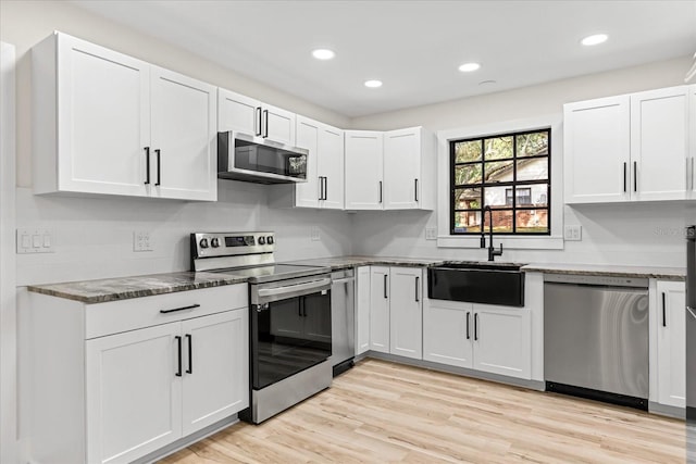 643 Princewood Dr, Deland, FL 32724 - kitchen with stainless steel appliances, white cabinetry, dark stone countertops, light wood finished floors, and recessed lighting