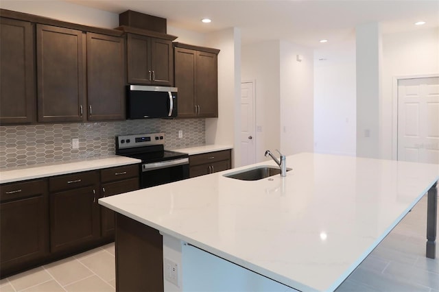 14568 Crestavista Ave, Clermont, FL 34714 - kitchen featuring appliances with stainless steel finishes, decorative backsplash, a kitchen island with sink, dark brown cabinetry, and recessed lighting