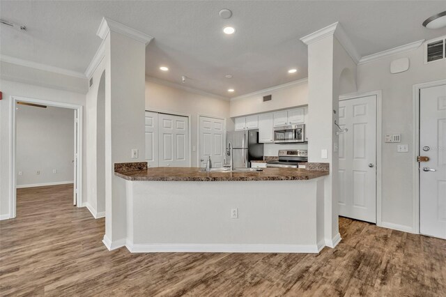 911 N Orange Ave Unit 443, Orlando, FL 32801 - kitchen with stainless steel appliances, crown molding, wood finished floors, white cabinetry, and recessed lighting
