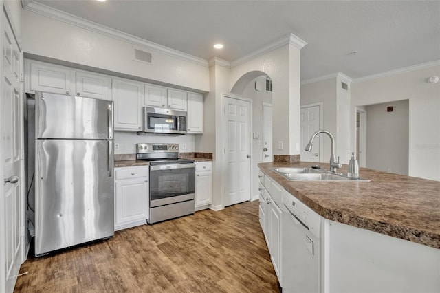 911 N Orange Ave Unit 443, Orlando, FL 32801 - kitchen with stainless steel appliances, ornamental molding, white cabinets, wood finished floors, and recessed lighting