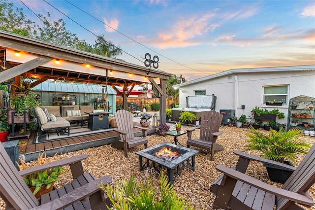 808 Camphor Way, Melbourne, FL 32901 - patio terrace at dusk featuring a hot tub, a gazebo, an outdoor living space with a fire pit, and a wooden deck
