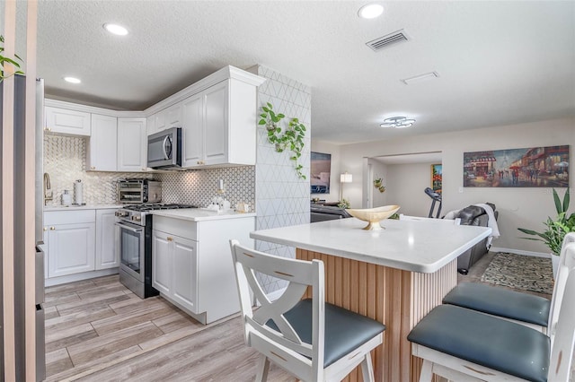 808 Camphor Way, Melbourne, FL 32901 - kitchen featuring stainless steel appliances, open floor plan, a breakfast bar, light countertops, and backsplash