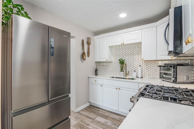 808 Camphor Way, Melbourne, FL 32901 - kitchen featuring appliances with stainless steel finishes, light countertops, backsplash, white cabinets, and light wood-type flooring