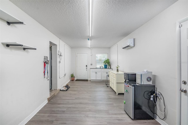 808 Camphor Way, Melbourne, FL 32901 - kitchen with a wall mounted AC, a textured ceiling, light wood finished floors, and white cabinetry