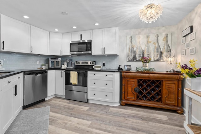 308 N Shadowbay Blvd Unit 214, Longwood, FL 32779 - kitchen with stainless steel appliances, dark countertops, white cabinets, a chandelier, and recessed lighting