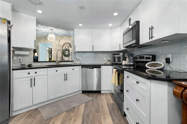308 N Shadowbay Blvd Unit 214, Longwood, FL 32779 - kitchen with stainless steel appliances, dark countertops, tasteful backsplash, white cabinetry, and a chandelier