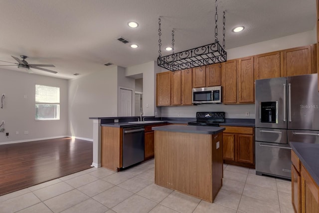 2237 Wintermere Pointe Dr, Winter Garden, FL 34787 - kitchen featuring appliances with stainless steel finishes, dark countertops, a center island, brown cabinetry, and recessed lighting
