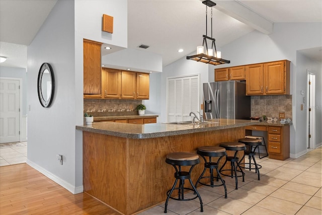 548 Timber Ridge Dr, Longwood, FL 32779 - kitchen with stainless steel fridge, dark countertops, tasteful backsplash, brown cabinetry, and beamed ceiling