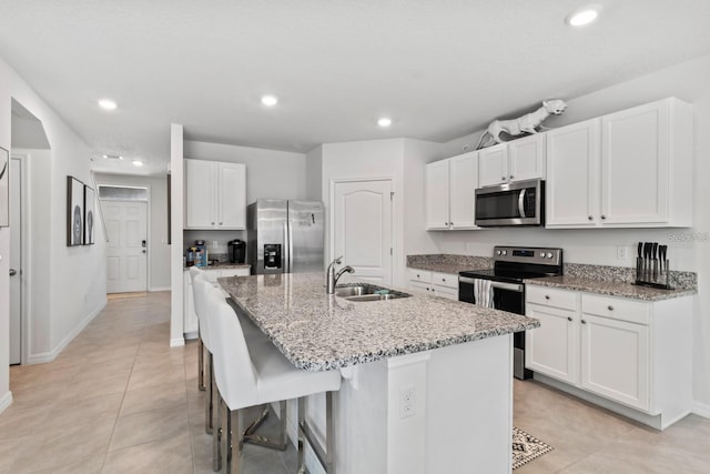 2355 White Lilly Dr, Kissimmee, FL 34747 - kitchen with stainless steel appliances, a center island with sink, white cabinets, light stone countertops, and recessed lighting
