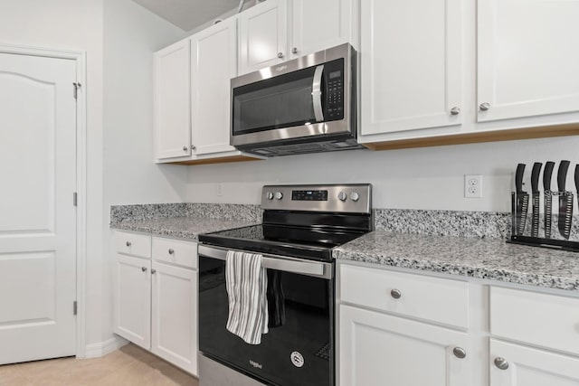 2355 White Lilly Dr, Kissimmee, FL 34747 - kitchen with stainless steel appliances, white cabinets, light stone countertops, and light tile patterned floors