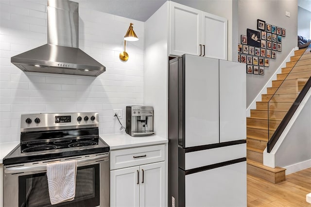 3706 Andover Cay Blvd, Orlando, FL 32825 - kitchen featuring stainless steel electric range, freestanding refrigerator, wall chimney range hood, light wood-style floors, and white cabinets