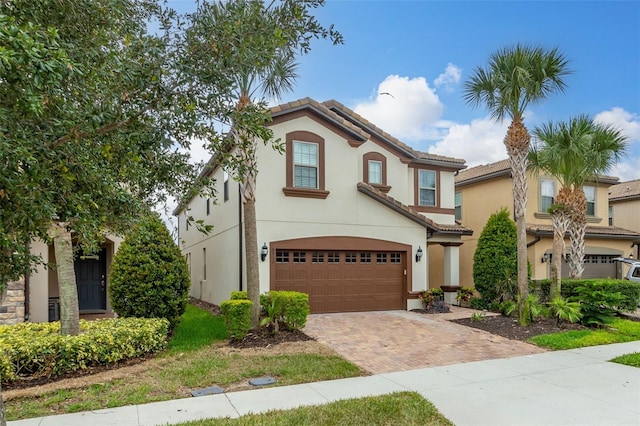 8912 Rhodes St, Kissimmee, FL 34747 - mediterranean / spanish home featuring an attached garage, decorative driveway, stucco siding, and a tiled roof