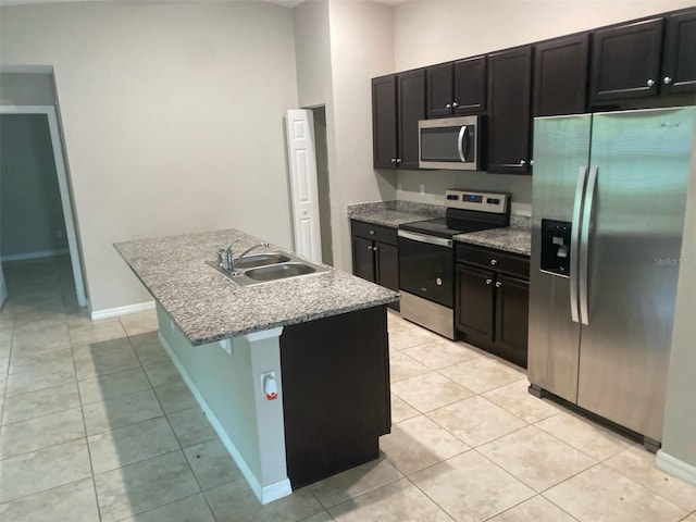 180 Ferguson St SE, Palm Bay, FL 32909 - kitchen featuring appliances with stainless steel finishes, light tile patterned flooring, a center island with sink, and dark cabinetry