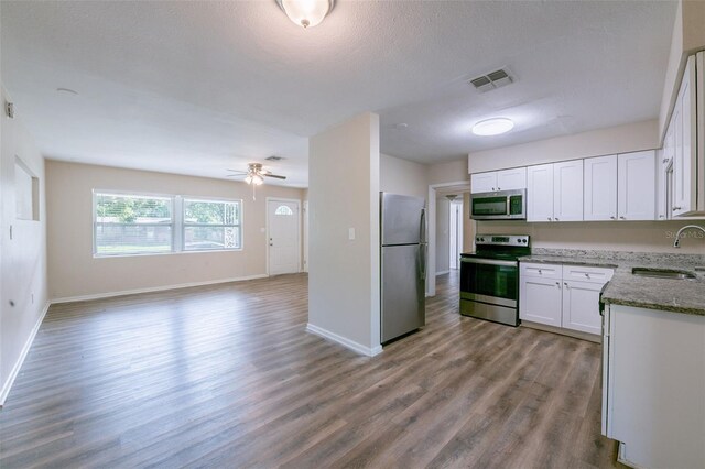 5908 Laconia Rd, Orlando, FL 32808 - kitchen with appliances with stainless steel finishes, wood finished floors, light stone counters, open floor plan, and white cabinetry