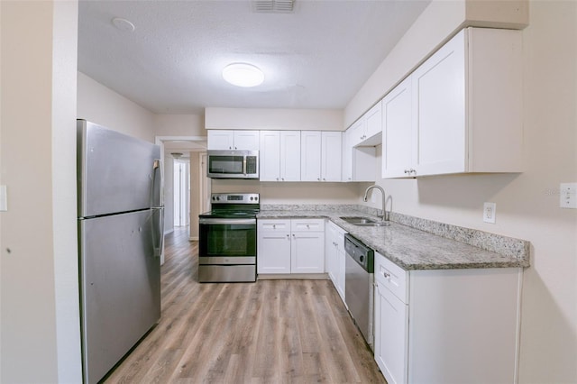 5908 Laconia Rd, Orlando, FL 32808 - kitchen with appliances with stainless steel finishes, light stone countertops, light wood finished floors, and white cabinetry