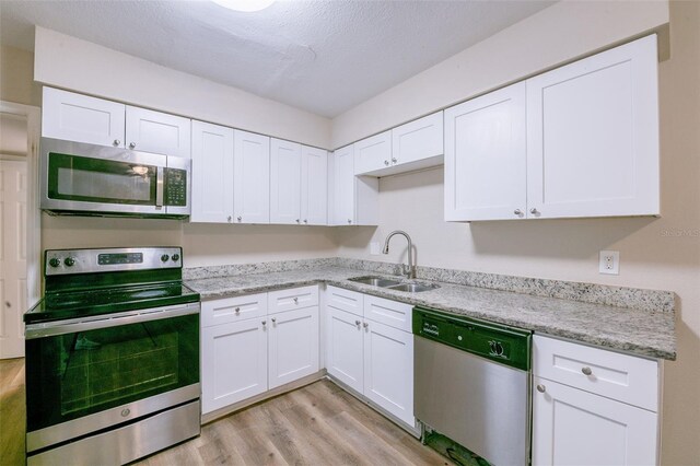 5908 Laconia Rd, Orlando, FL 32808 - kitchen with appliances with stainless steel finishes, light wood-style floors, white cabinets, light stone countertops, and a textured ceiling