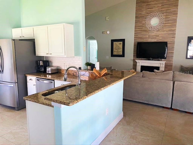 2650 Autumn Creek Cir, Kissimmee, FL 34747 - kitchen with high vaulted ceiling, stainless steel appliances, dark stone countertops, white cabinets, and a peninsula