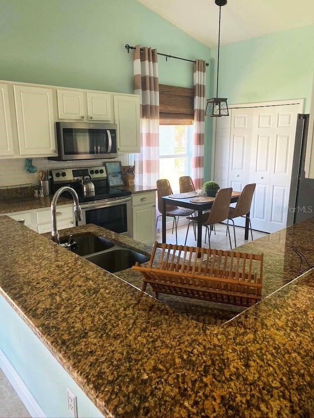 2650 Autumn Creek Cir, Kissimmee, FL 34747 - kitchen featuring stainless steel appliances, tasteful backsplash, lofted ceiling, white cabinets, and hanging light fixtures