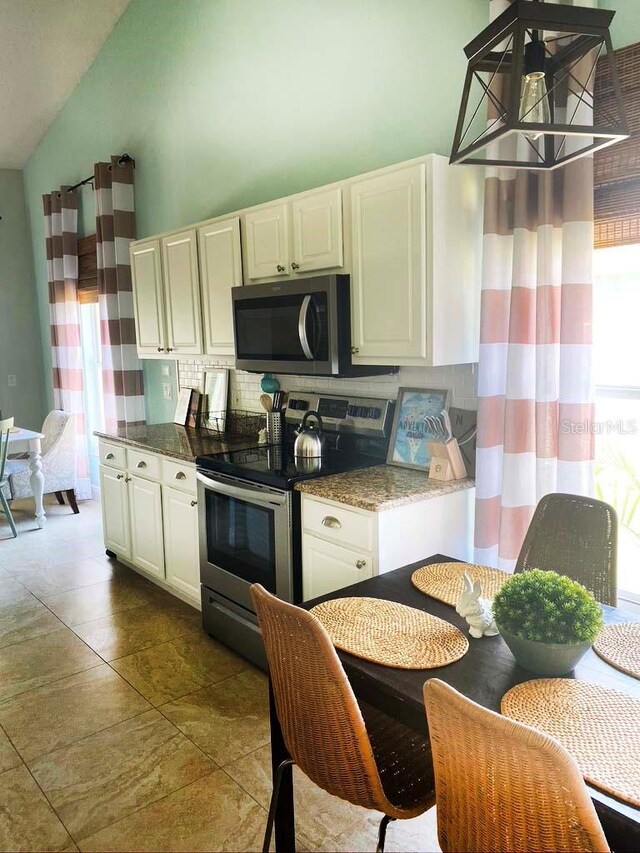 2650 Autumn Creek Cir, Kissimmee, FL 34747 - kitchen featuring appliances with stainless steel finishes, tasteful backsplash, lofted ceiling, white cabinetry, and stone countertops