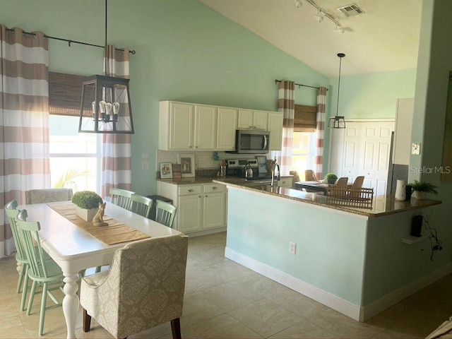 2650 Autumn Creek Cir, Kissimmee, FL 34747 - kitchen with stainless steel microwave, lofted ceiling, rail lighting, range, and backsplash