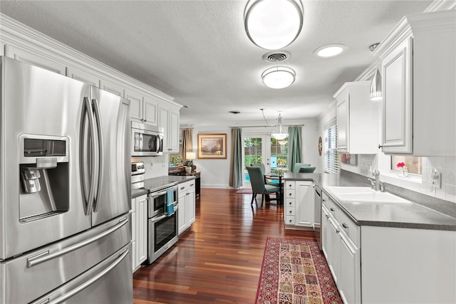 2312 S Summerlin Ave, Orlando, FL 32806 - kitchen with stainless steel appliances, backsplash, white cabinets, dark countertops, and a textured ceiling