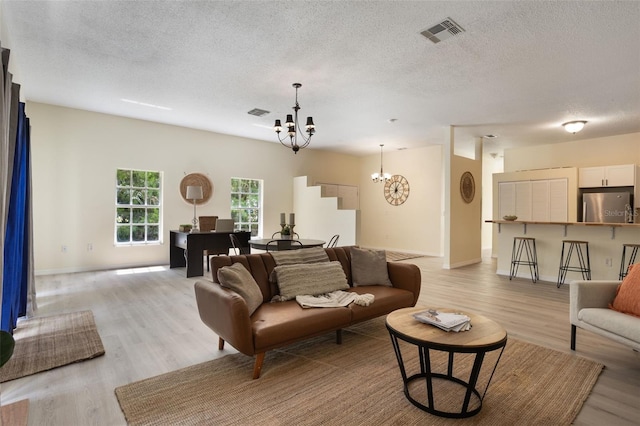 1065 Universal Rest Pl, Kissimmee, FL 34744 - living room featuring a chandelier, light wood-style flooring, and a textured ceiling
