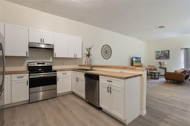 1065 Universal Rest Pl, Kissimmee, FL 34744 - kitchen with stainless steel appliances, under cabinet range hood, butcher block counters, a peninsula, and light wood-style floors