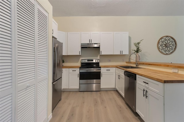 1065 Universal Rest Pl, Kissimmee, FL 34744 - kitchen with appliances with stainless steel finishes, butcher block countertops, under cabinet range hood, light wood-style flooring, and a peninsula