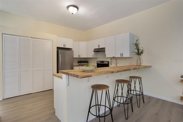 1065 Universal Rest Pl, Kissimmee, FL 34744 - kitchen featuring wood counters, freestanding refrigerator, under cabinet range hood, light wood-style flooring, and a textured ceiling