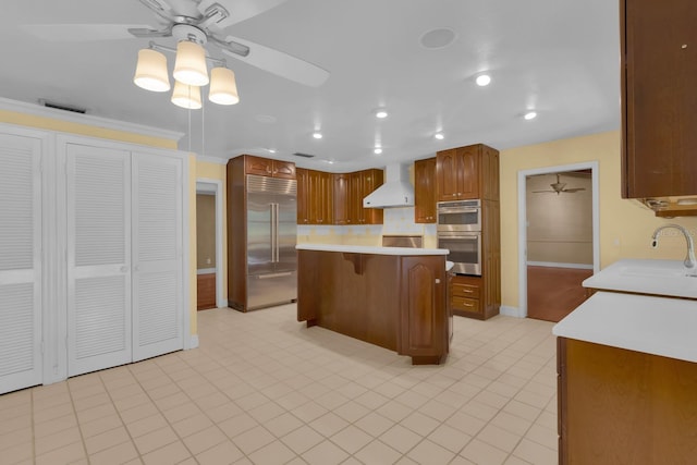 202 Riverview Dr, Longwood, FL 32779 - kitchen featuring appliances with stainless steel finishes, ceiling fan, wall chimney exhaust hood, light countertops, and a kitchen breakfast bar