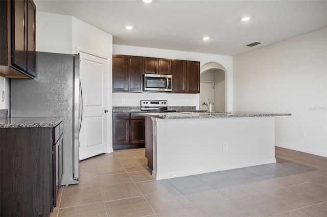 17127 Harvest Moon Way, Bradenton, FL 34211 - kitchen featuring appliances with stainless steel finishes, dark brown cabinets, stone counters, a kitchen island with sink, and recessed lighting