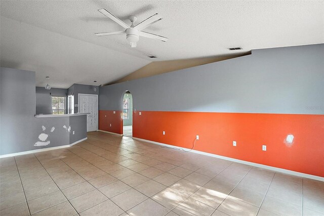 979 Mayfair St, Eustis, FL 32726 - unfurnished living room with ceiling fan, arched walkways, tile patterned flooring, lofted ceiling, and a textured ceiling